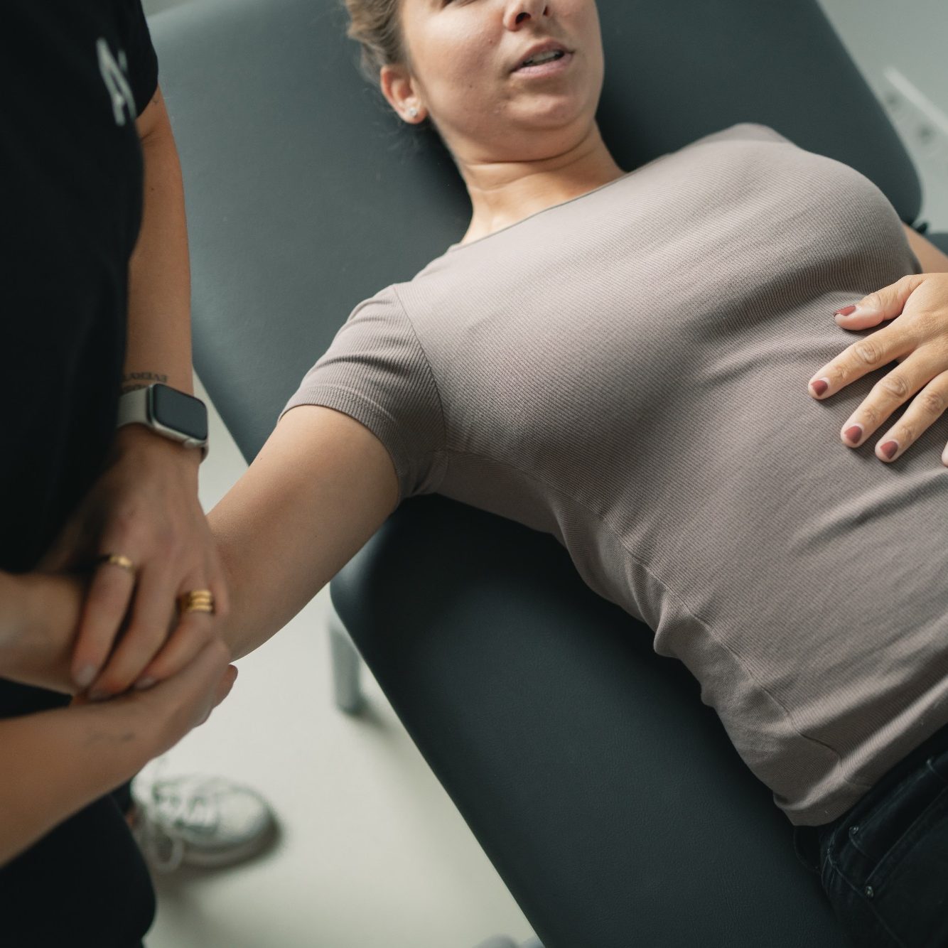 Ein Therapeut behandelt eine liegende Patientin manuell.