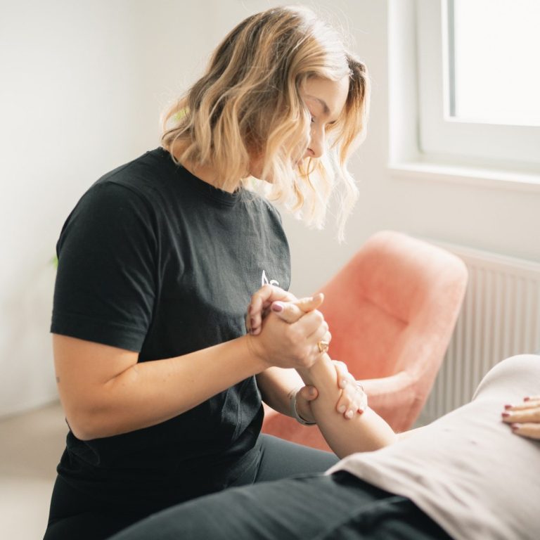 Eine Person macht eine Handgelenkmassage an einem liegenden Arm.