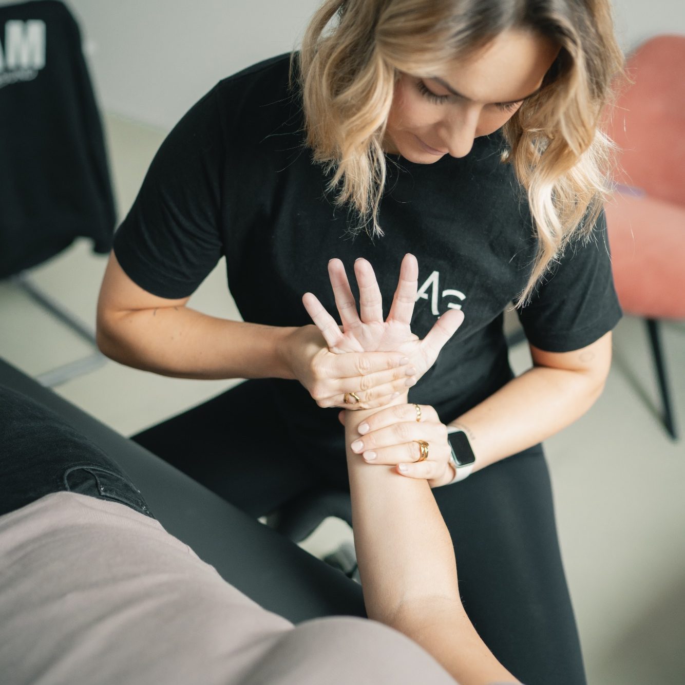 Ein Therapeut behandelt eine liegende Patientin manuell.