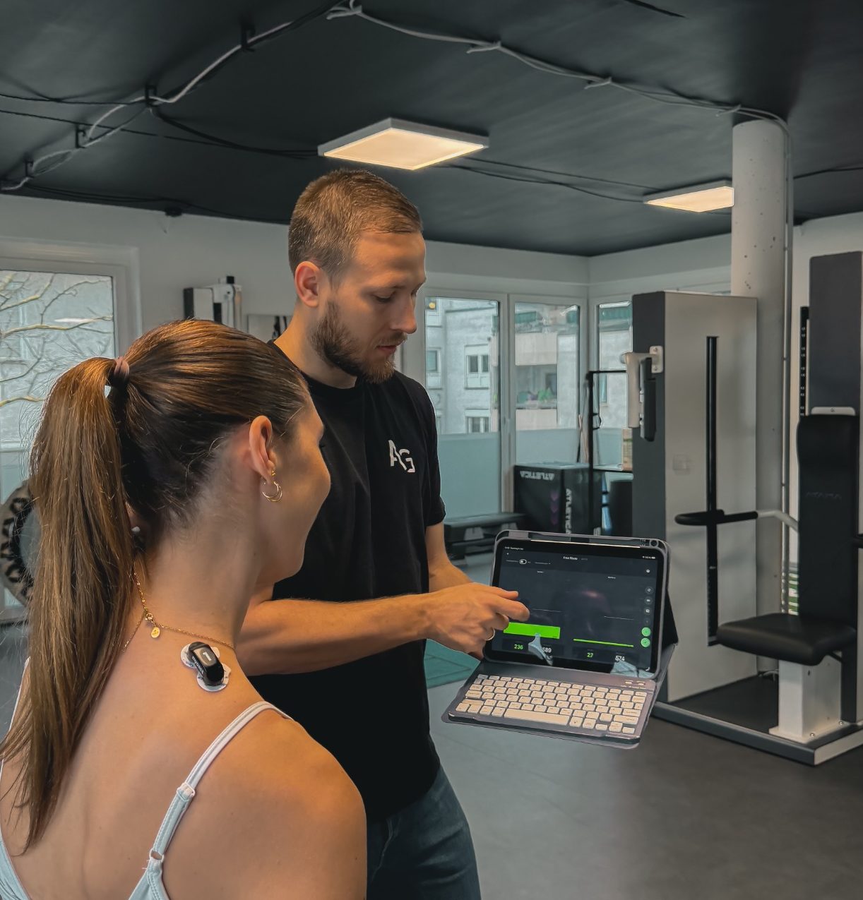 Frau massiert die Hand einer Person auf einer Liege in einem hellen Raum.